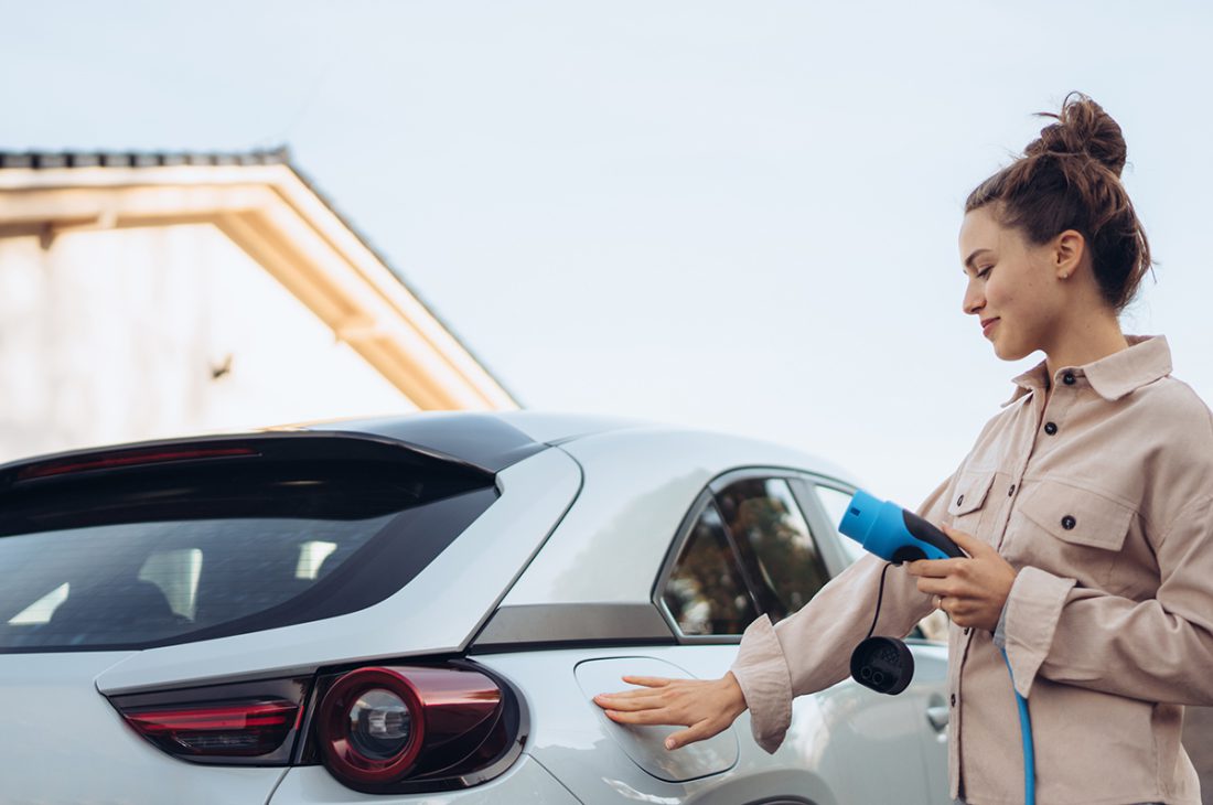 Une femme heureuse après avoir rechargé son véhicule grâce à sa borne de recharge électrique