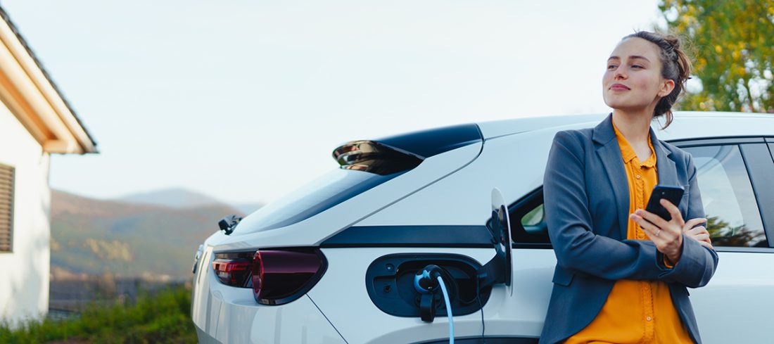 Une femme chargeant son véhicule grâce à sa borne de recharge électrique installée chez elle